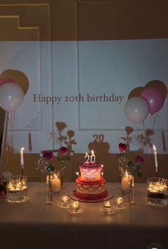 a birthday cake sitting on top of a table next to candles and flowers in vases