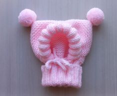 a pink knitted hat with pom - poms