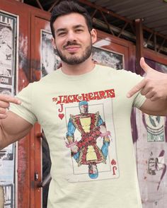 a man wearing a jack of hearts t - shirt giving the thumbs up while standing in front of a building