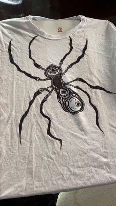 a white t - shirt with a black spider on it