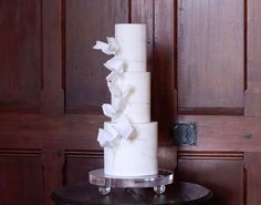 a tall white cake sitting on top of a table next to a wooden paneled wall