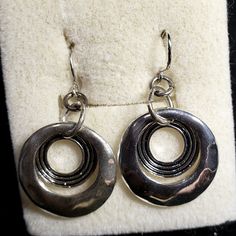 These Vintage New Double Circle Earrings Are From Piercing Pagado In Its Original Box. The Earrings Have A Solid Silver Circle On The Outer Layer With A Dangling Smaller Silver Circle With Three Black Ribbed Outlines. Fish Hook Style. This Item Comes Gift Wrapped For Free. Perfect For Mother's Day, A Summer Party Or A Birthday Gift. Buy Multiple Items In A Bundle And Save More Money. Stud Aesthetic, Silver Circle Earrings, Boho Lifestyle, Large Statement Earrings, Save More Money, Bling Earrings, Silver Bling, Heart Hands, Silver Circle