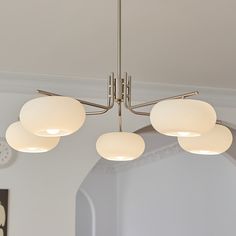 three circular lights hanging from the ceiling in a living room with white walls and flooring