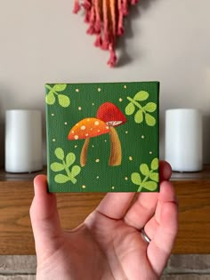 a hand holding up a small card with a mushroom on it's front and green background