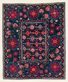 a blue and red rug with flowers on the bottom, surrounded by smaller floral designs