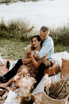 a man and woman sitting on top of a blanket