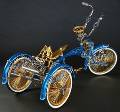 a miniature blue and gold bike on a black background