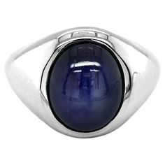 Discover distinguished men's ring features a stunning natural blue star sapphire, set in a classic 14K white gold band. The star sapphire is renowned for its unique star-like phenomenon, known as asterism, which appears on the surface when viewed under direct light. This impressive gemstone, combined with the sleek white gold setting, creates a bold and sophisticated piece perfect for any occasion. Center Stone: Natural Burma Blue Star Sapphire Quantity & Weight: The ring features one star sapph White Star Sapphire Ring, Blue Star Sapphire Rings For Men, Star-shaped Blue Birthstone Jewelry, Blue Star Sapphire Rings, Blue Star-shaped Gemstone Ring, Star Sapphire Stone, Mens White Gold Rings, Star Sapphire Gemstone, Blue Star Sapphire