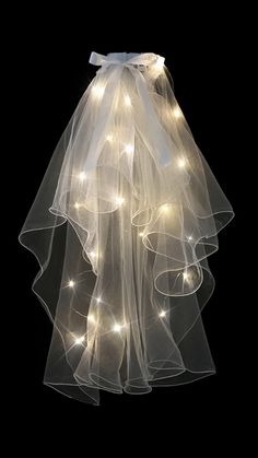 a white veil with lights hanging from it's side on a black background,