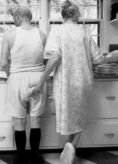 two people are standing in the kitchen looking at something on the stove top and oven