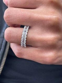 a woman's hand wearing a white gold ring with baguettes on it