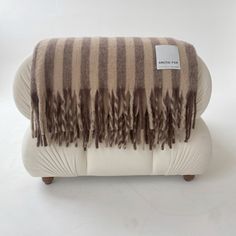 a brown and white striped blanket sitting on top of a couch next to a pillow