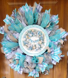 a blue and white wreath on the front door is decorated with flowers, ribbons and ribbon