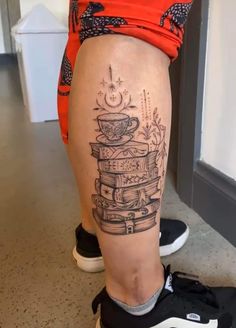 a person with a stack of books tattoo on their leg