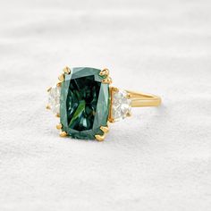 ✦ The Ring Shown in the Picture Holds a Beautiful 6.3 CT Dark Green Cushion Moissanite and is Size 6 US. ✦ Main Stone Details✧ Shape: Dark Green Cushion Cut Moissanite✧ Weight: 6.3 CT ✧ Color: DEF(Colorless)✧ Clarity: VVS✦ Side Stone Details✧ Shape: Half Moon & Round Moissanite✧ Weight: 0.8 CT (App.)✧ Color: DEF (Colorless)✧ Clarity: VVS✦ Ring Details✧ Band Width: 1.5 mm (± 0.10) [Customized Possible]✧ Metal: Gold (10KT, 14KT, 18KT)✧ Metal Tone: Yellow, White, Rose Dark Green Cushions, Cushion Cut Moissanite, Green Cushions, Types Of Diamonds, Emerald Engagement, Round Moissanite, Emerald Engagement Ring, Recycled Gold