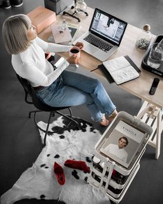 a woman sitting at a desk with a glass of wine in front of her laptop