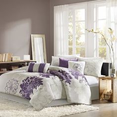 a bed with purple and white comforters in a bedroom