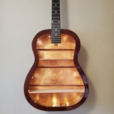 an acoustic guitar hanging on the wall with its light up display case in front of it