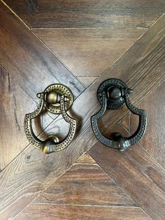 two antique style door handles on a wooden door with wood grained flooring in the background