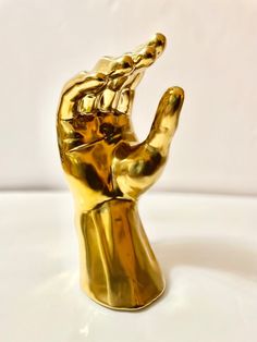 a gold colored hand statue on a white surface