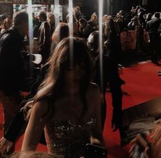 a woman walking down a red carpet covered in people