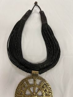 Add a touch of African culture to your jewelry collection with this handcrafted leather necklace. The necklace features a gold weight pendant made of brass, which adds a touch of elegance to the overall look. The pendant hangs on a bronze chain, which complements the brass metal purity and the main stone color. The necklace is perfect for anyone who wants to explore African ethnic and regional style. It is a unique piece of jewelry that will stand out in any collection. African Culture, Choker Necklaces, Handcrafted Leather, Leather Necklace, Brass Metal, Necklace Gold, Stone Color, Unique Pieces, Choker Necklace