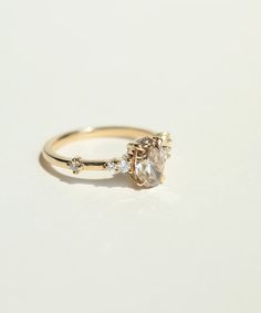 a yellow gold ring with an oval cut diamond and three small diamonds on the side