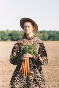 a woman holding carrots in an open field