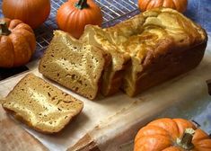 a loaf of bread sitting on top of a wooden cutting board next to pumpkins