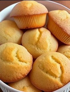 a white bowl filled with muffins on top of a wooden table