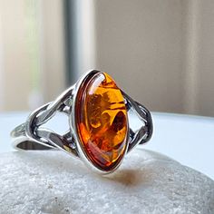 NATURAL BALTIC COGNAC AMBER RING Immerse in elegance with our Amber Ring-- a captivating blend of minimalist style and timeless charm. Crafted to perfection, this eye-catching ring radiates sophistication, making it the perfect accessory for any occasion. Discover the perfect expression of love and appreciation with our curated selection of the best gifts for her. ITEM SPECIFICATIONS * Materials: Baltic Amber, 925 Sterling Silver. * Stone color: Honey. * Stone size: 0.5" x 0.27" (13 mm x 7mm). * Amber Rings, Sterling Silver Amber Gemstone Rings, Baltic Amber Ring, Unique Amber Sterling Silver Rings, Luxury Amber Sterling Silver Rings, Handmade Amber Sterling Silver Rings, Nature-inspired Amber Sterling Silver Jewelry, Fossil Ring, Amber Ring