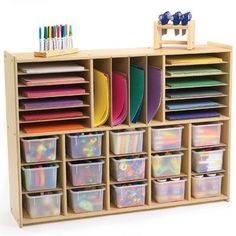 a wooden storage unit filled with lots of different colored plastic bins and trays