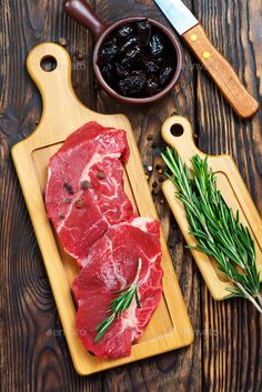 raw meat on wooden cutting board with olives and rosemary - stock photo - images