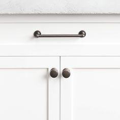 a close up view of the handles on a white cabinet with two doors and one drawer