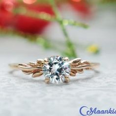 a close up of a ring on a table with flowers in the background and a red rose behind it