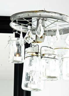 mason jar chandelier hanging from the ceiling in a room with black framed mirror