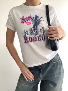 Beer Rodeo 90s Baby Tee, Coors Cowboys tshirt 90's YOUTH baby tee style tshirts! These are YOUTH TEES for the classic 90s baby tee look! Hi! If you have any questions or want to make changes to your order, please message me. ⭐HOW TO ORDER - Please Choose the SIZE and COLOR From Drop Down Menu. ⭐MATERIAL - Cotton Polyester blend fabrics with direct to garment process. Everything is made in house. ⭐SHIPPING - Processing times can verify, dark color shirts do take longer to make, it should take abo Vintage Summer T-shirt For Rodeo, Graphic Tee For Rodeo And Spring, Spring Graphic Tee For Rodeo, Spring Rodeo Graphic Tee, Retro Summer T-shirt For Rodeo, Retro Summer Rodeo T-shirt, White Crew Neck T-shirt For Rodeo, Trendy Cotton T-shirt For Rodeo, Trendy Relaxed Fit T-shirt For Rodeo