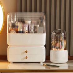 two white drawers with pens and pencils in them next to a clock on a table