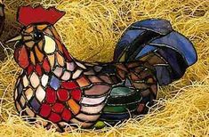 a stained glass rooster sitting on top of hay