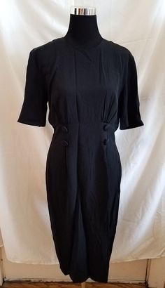 Sleek vintage black dress from the 1980s. Silky and lightweight polyester fabric (no stretch). Button-up back closure with invisible zipper on the skirt. No major flaws - wonderful condition! Measurements (taken flat): -Bust: 20 inches -Waist: 15.5 inches -Hips: 21.5 inches No returns or exchanges. Please read the description and measurements carefully. Contact the seller directly with any issues. Black Button-back Dress For Work, Black Workwear Dress With Button Back, Black Work Dress With Button Back, Formal Fitted Vintage Dress, Fitted Button Back Midi Dress For Work, Fitted Midi Dress With Button Back For Work, Elegant Vintage Dress With Button Closure For Work, Classic Fitted Black Vintage Dress, Fitted Black Classic Vintage Dress