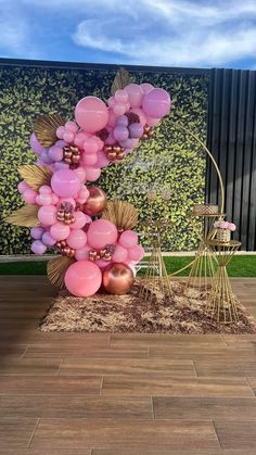 the balloon sculpture is made out of pink and gold balloons, with golden leaves on top