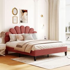 a bedroom with white walls and wooden floors, pink bedspread on the bed