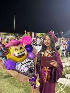 a woman in graduation gown standing next to balloons and balloon bouquets at an event