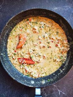 a skillet filled with food on top of a black counter next to a knife