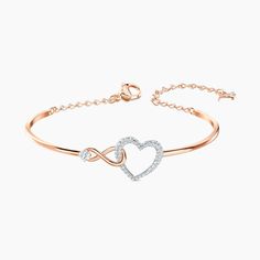 This heart bracelet combines the precision and quality of sparkling crystals with a chic rhodium plated chain, making this endearing look a cute accessory. A single white crystal adorns a dainty infinity sign interlaced with a dazzling white crystal pave heart, adding a brilliant and romantic touch to the simple, refined design. Rose Gold Metal Heart Bangle Bracelet, Rose Gold Heart Bangle Bracelet, Elegant Metal Heart Bracelet For Party, Elegant Metal Crystal Bracelet For Valentine's Day, Rose Gold Metal Heart Bangle, Rose Gold Crystal Bracelet For Anniversary, Elegant Rose Gold Crystal Bracelet, Elegant Valentine's Day Party Chain Bracelet, Heart-shaped Rose Gold Bracelets For Party