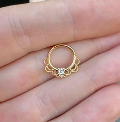 a person is holding an open gold ring with a diamond on the inside of it