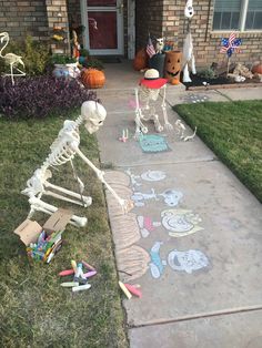 two skeletons painted on the sidewalk in front of a house with halloween decorations around them