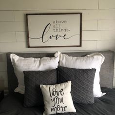 a bed with two pillows and a framed sign above it that says above all things love