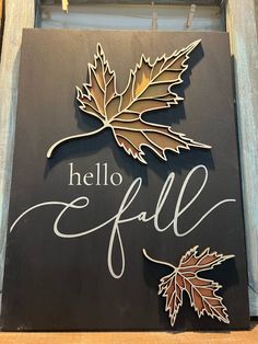 a sign that says hello fall with two leaves on the front and back of it