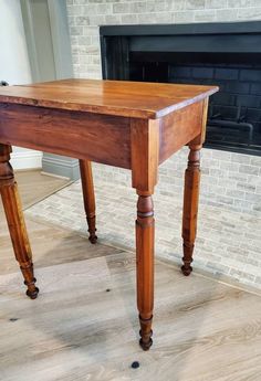 a wooden table sitting on top of a hard wood floor next to a fire place